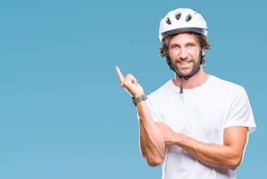 Yüzünde kocaman bir gülümseme ile izole arka plan üzerinde güvenlik kask giymiş yakışıklı İspanyol bisikletçi adam kameraya bakarak yan el ve parmak ile işaret.