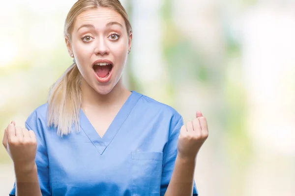 若い金髪外科医医師女性以上医療制服を着て腕を上げると 驚きと驚きの成功を祝っての背景を分離し 目を開きます 勝者の概念 — ストック写真