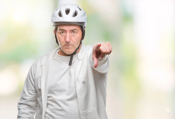 Handsome senior cyclist man wearing bike helmet over isolated background pointing with finger to the camera and to you, hand sign, positive and confident gesture from the front