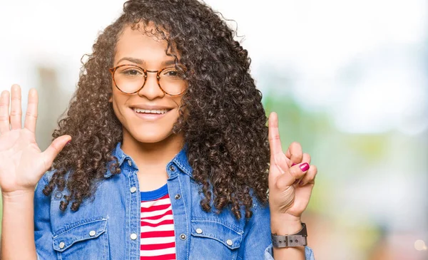 Young beautiful woman with curly hair wearing glasses showing and pointing up with fingers number six while smiling confident and happy.