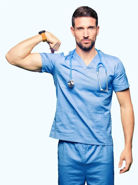 英俊的医生在孤立的背景上穿上医疗制服的坚强的人表现出手臂肌肉 自信和自豪的力量 — 图库照片