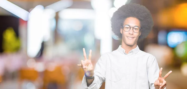 勝利のサインをやって指を表示するカメラを笑みを浮かべてアフロ髪メガネの若いアフリカ系アメリカ人 — ストック写真