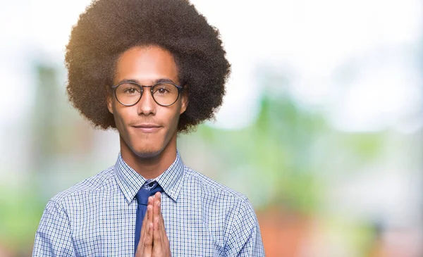 眼鏡をかけて祈って許しは自信を持って笑顔を求めて一緒に手でアフロの髪の若いアフリカ系アメリカ人ビジネス男 — ストック写真