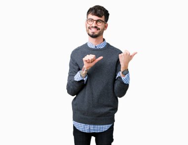 Genç yakışıklı izole arka plan üzerinde gözlüklü adam akıllı emin gülümseyen arkasından el ve kadar başparmak ile işaret