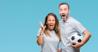 Orta yaş İspanyol çift futbol futbol topu tutan kocaman bir gülümseme ile çığlık zaferini kutluyor ve ellerini kaldırdı arka plan çok mutlu ve heyecanlı, kazanan ifade izole