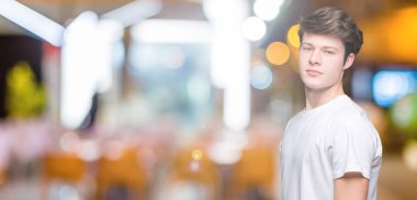 Genç yakışıklı giyiyor rahat beyaz t-shirt yüzünde ciddi bir ifade ile izole arka plan üzerinde adam. Basit ve doğal kameraya bakıyor.