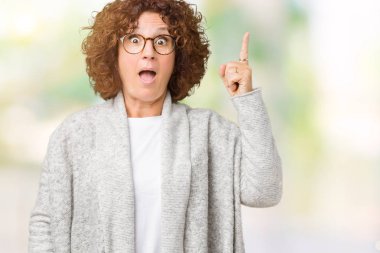 Ceket ve gözlük izole arka plan üzerinde işaret parmağı kadar başarılı fikirle giyen güzel orta ager üst düzey kadın. Çıktıktan ve mutlu. Bir numara.