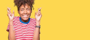 Umut ve gözleri kapalı geçiş parmaklarıyla gülümseyen izole arka plan güzel genç Afro-Amerikan kadın. Şans ve batıl kavramı.