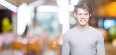 Yüzünde mutlu ve güzel bir gülümseme ile izole arka plan üzerinde kış kazak giyen genç yakışıklı adam. Şanslı kişi.