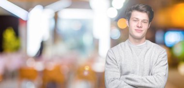 Mutlu yüz ile gülümseyerek kameraya seyir silah geçti arka plan üzerinde sweatshirt giyen genç yakışıklı sportif adam izole. Olumlu bir kişi.