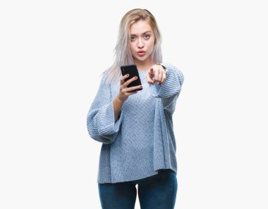 Sarışın genç kadın manifatura üzerinden Smartphone kullanarak ileti gönderme kamera ve size parmak ile işaret arka plan izole, el işareti, pozitif ve kendinden emin bir jest ön