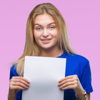 Boş kağıt sayfası izole arka plan üzerinde duran ve diş gösterilen kendine güvenen bir gülümsemeyle gülümseyerek mutlu bir yüz tutan genç beyaz kadın