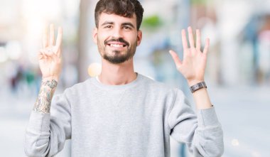 Gösterilen arka plan üzerinde sweatshirt giyen genç yakışıklı adam izole ve parmakları ile işaret kendinden emin ve mutlu gülümseyerek süre 8 numaralı.