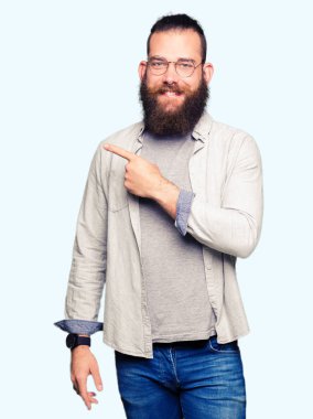 Neşeli bir gülümseme ile el ve parmak kadar yan yüzünde mutlu ve doğal ifade ile işaret yüz ile gözlüklü genç sarışın adam