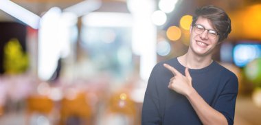 İzole arka neşeli bir gülümseme ile el ve parmak kadar yan yüzünde mutlu ve doğal ifade ile işaret yüz üzerinden gözlüklü genç yakışıklı adam