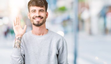 Kazak izole arka plan Waiving mutlu selam söyleyerek üzerinde ve gülümseyen, dostça karşılama jest giyen genç yakışıklı adam