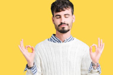 Genç yakışıklı adam giyen kış kazak izole arka plan üzerinde dinlenmek ve gülümseyen gözlerle parmak ile meditasyon jest yapıyor kapalı. Yoga kavramı.