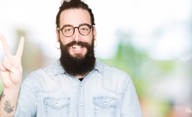 Uzun saç ve sakal gösterilen ve parmakları ile işaret gözlüklü genç hipster adamla ikincisi ise kendinden emin ve mutlu gülümseyerek.