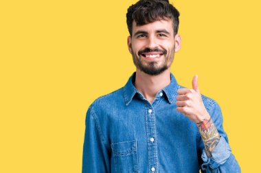 Yakışıklı delikanlı hareketi el ile mutlu yaşasın yapıyor izole arka plan üzerinde. Başarı gösteren kameraya bakarak ifade onaylama.