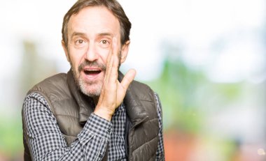 Orta yaş yakışıklı adam giyen kış yelek el gizli söylenti, kötü niyetli konuşma konuşma fısıldayarak söylemek dudaklarından