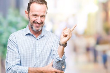 Kameraya bakarak yan el ve parmak ile işaret orta yaş ağarmış üst düzey iş adamı yüzünde kocaman bir gülümseme ile izole arka plan üzerinde.