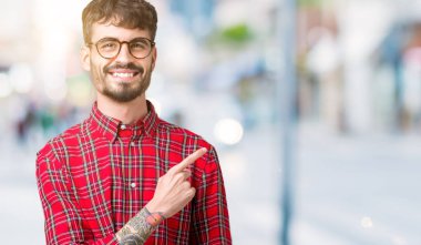 İzole arka neşeli bir gülümseme ile el ve parmak kadar yan yüzünde mutlu ve doğal ifade ile işaret yüz üzerinden gözlüklü genç yakışıklı adam