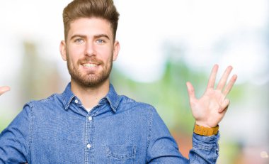 Genç yakışıklı sarışın adam gösterilen ve parmakları ile işaret rahat kot gömlek giymiş numara 9 kendinden emin ve mutlu gülümseyerek süre.