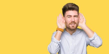 Genç ve yakışıklı bir adam iki elini de kulak hareketi yaparken duymaya çalışıyor. Dedikoduya meraklı. İşitme problemi, sağır