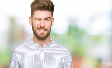 Yakışıklı delikanlı seksi bir ifadeyle, neşeli ve mutlu yüzünü kameraya bakarak göz kırpıyor.