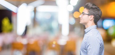 Genç yakışıklı adam gözlük izole arka tarafına, seyir üzerinde dinlenmek doğal yüz emin gülümseme ile pozuyla profili.