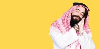 Arap iş adamı uzun saçlı geleneksel keffiyeh şal uyku yorgun hayal ve ile gülümseyen gözleri kapalı iken ellerle birlikte poz.