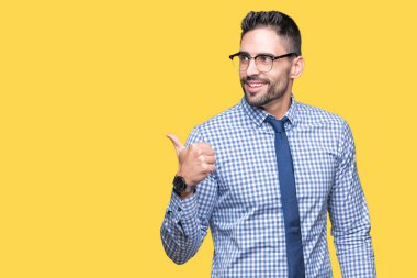 Seyir ve başparmak yanında yukarıyı mutlu yüz ile gülümseyen izole arka plan üzerinde gözlük takan genç iş adamı.