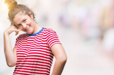 Casual göz yapıyor gülümseyen izole arka plan üzerinde giyen güzel esmer kıvırcık saçlı Genç kız telefon hareketi ile el ve parmak telefonda konuşuyor gibi. Kavramları iletişim.