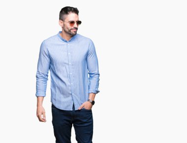 Genç yakışıklı adam uzak tarafına yüzünde, doğal ifade gülümseme ile seyir izole arka plan üzerinde güneş gözlüğü takıyor. Kendine güvenen gülüyor.