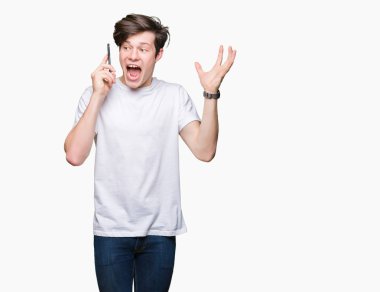 Smartphone üzerinde kocaman bir gülümseme ile çığlık zaferini kutluyor ve ellerini kaldırdı izole arka plan çok mutlu ve heyecanlı, kazanan ifade üzerinde konuşan genç adam