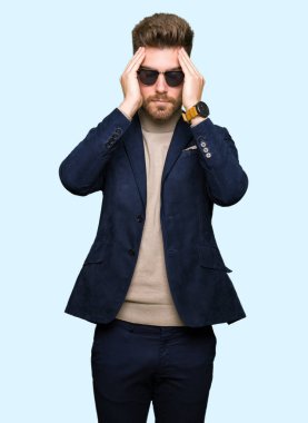 Genç yakışıklı zarif adam giyen güneş gözlüğü çünkü umutsuz ve stresli baş ağrısı acı acı ve migren. Ellerini kafasına.