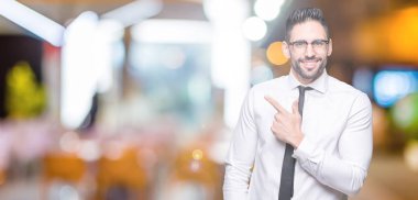 İzole arka neşeli bir gülümseme ile el ve parmak kadar yan yüzünde mutlu ve doğal ifade ile işaret yüz üzerinden gözlüklü genç yakışıklı iş adamı