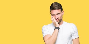 Casual beyaz t-shirt düşünme seyir giyen yakışıklı adam yorgun ve sıkılmış çapraz silah depresyon sorunları ile.