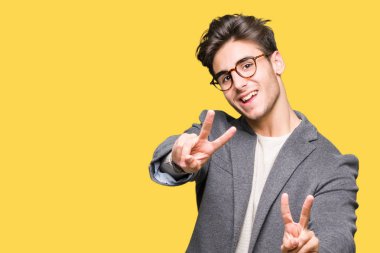 Zafer işareti yapıyor parmak gösterilen kamera seyir gülümseyen izole arka plan üzerinde gözlük takan genç iş adamı. İki numaralı.