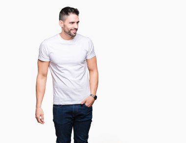 Uzak tarafına yüzünde, doğal ifade gülümseme ile seyir izole arka plan üzerinde rahat beyaz t-shirt giyen genç adam. Kendine güvenen gülüyor.