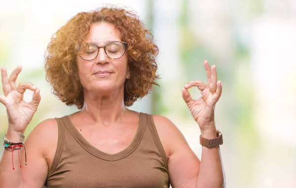 中年西班牙妇女戴眼镜在孤立的背景放松和微笑闭着眼睛用手指做冥想手势 瑜伽概念 — 图库照片