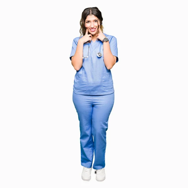指を指すと 陽気な笑顔を強制口を開けて 医療制服笑顔を身に着けている若い大人医師女性 — ストック写真