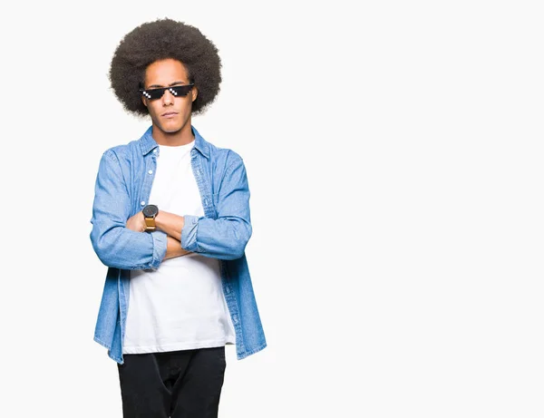 Young african american man with afro hair wearing thug life glasses skeptic and nervous, disapproving expression on face with crossed arms. Negative person.