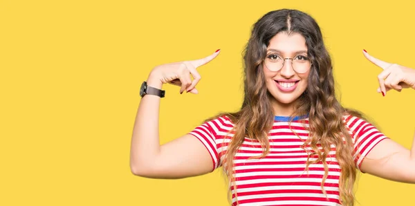 Joven Hermosa Mujer Con Gafas Sonriente Apuntando Cabeza Con Ambas —  Fotos de Stock