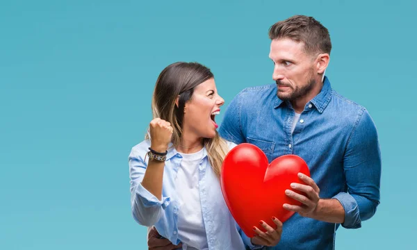 Pareja Joven Enamorada Sosteniendo Corazón Rojo Sobre Fondo Aislado Molesta — Foto de Stock