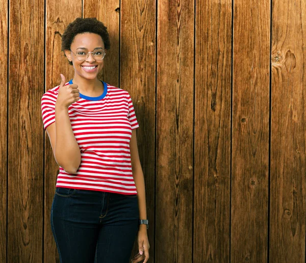 Güzel genç Afro-Amerikan kadın hareketi el ile mutlu yaşasın yapıyor izole arka plan üzerinde gözlük takıyorum. Başarı gösteren kameraya bakarak ifade onaylama.