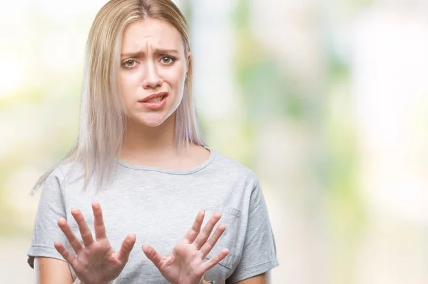 Young blonde woman over isolated background disgusted expression, displeased and fearful doing disgust face because aversion reaction. With hands raised. Annoying concept.