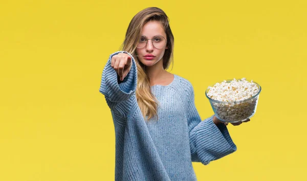 若い美しいブロンドの女性の上でポップコーンを食べる分離カメラと指で指している背景 手署名 正面からポジティブで自信のジェスチャー — ストック写真