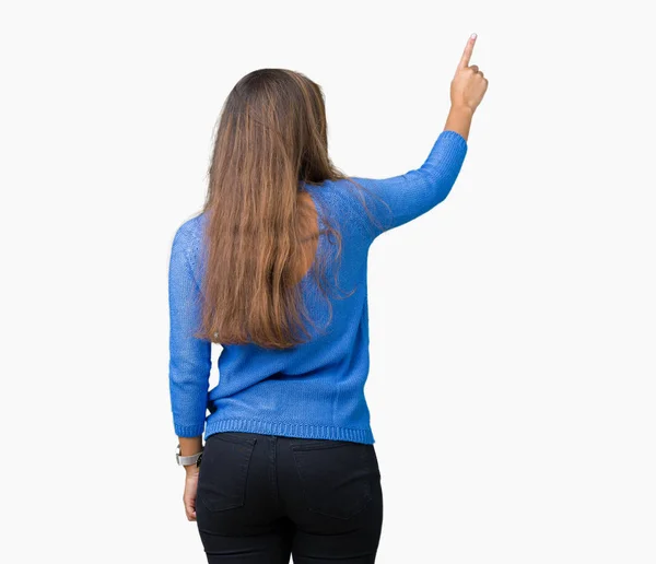 分離の上青いセーターを着ている若い美しいブルネットの女性背景指手の背後後方を指すポーズ — ストック写真