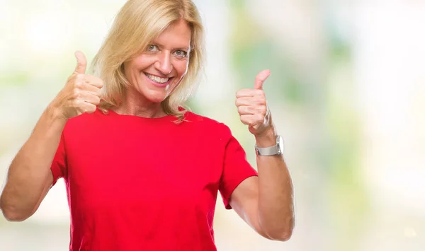 Middle age blonde woman over isolated background success sign doing positive gesture with hand, thumbs up smiling and happy. Looking at the camera with cheerful expression, winner gesture.